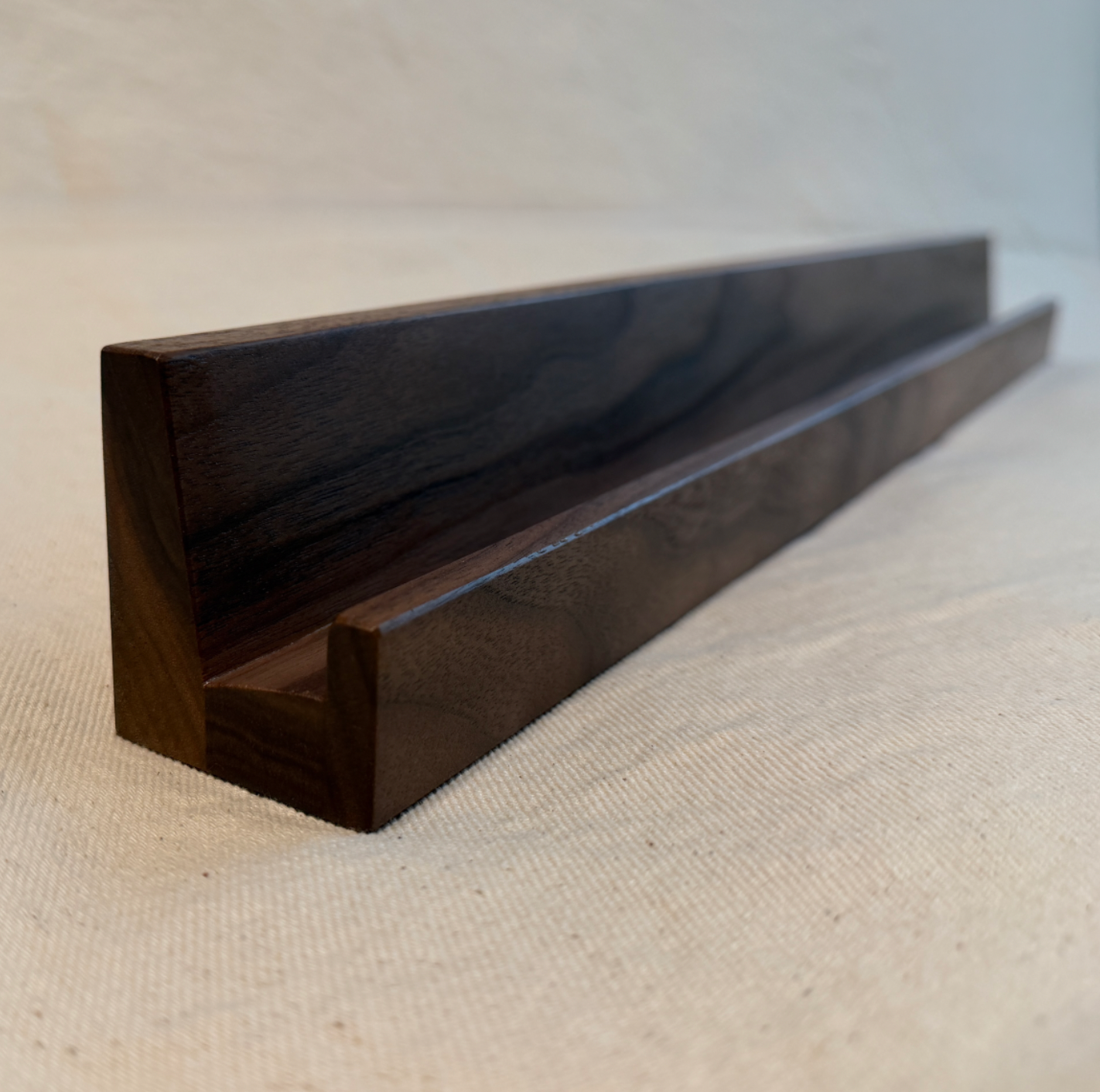 Dark wooden shelf on a beige surface with a neutral background